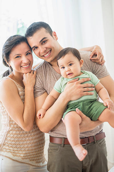 mother and father hugging and smiling holding their baby