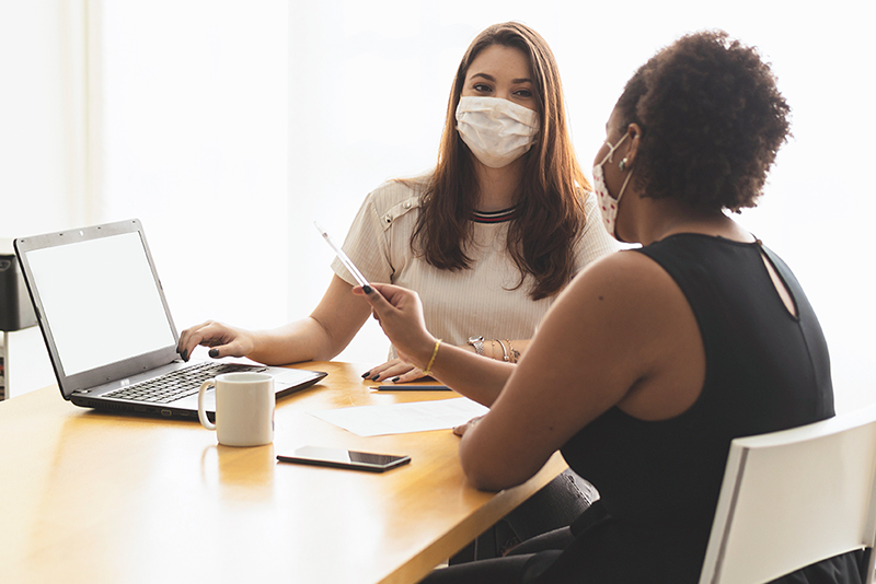 two women wearing masks meeting