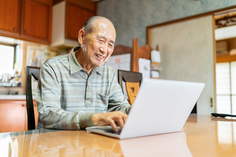 older gentleman sitting at table on laptop