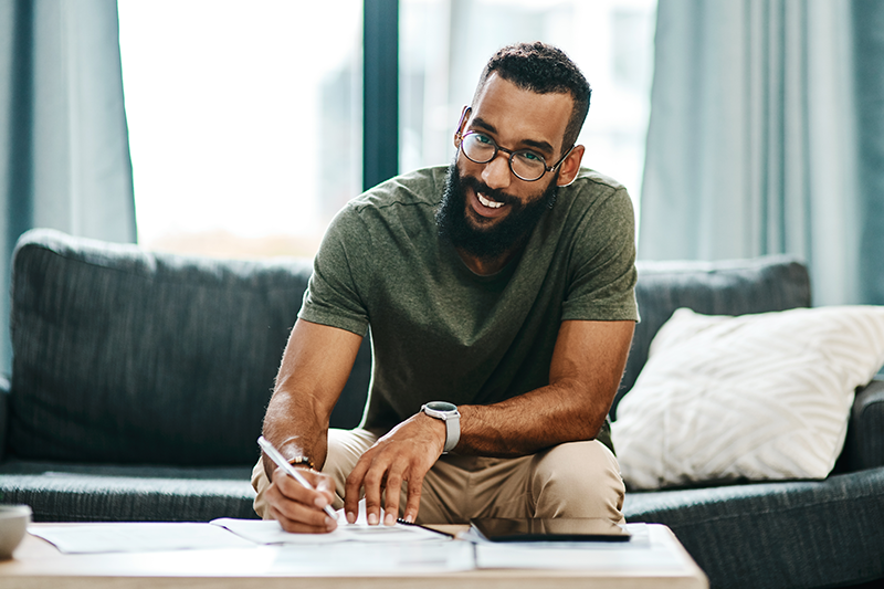 man sitting down filling out paperwork and smiling