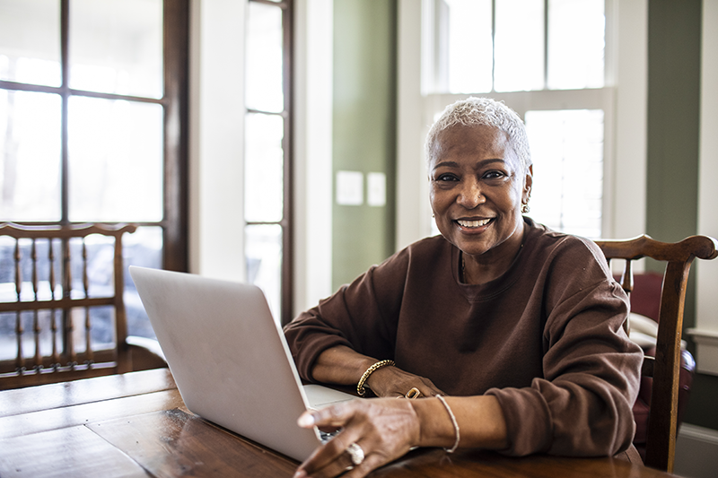 woman sitting in front of a laptop looking at the camera and smiling