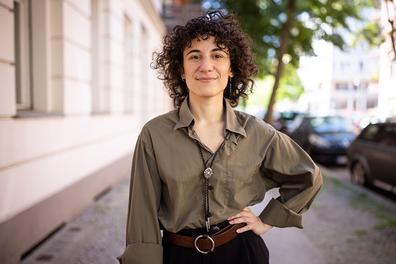 non binary individual standing outside court building on sidewalk