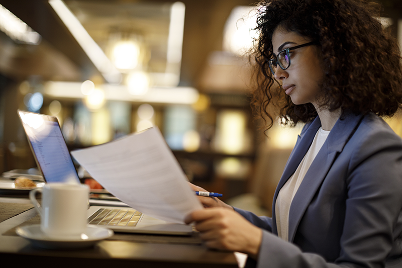 woman holding paper looking at computer