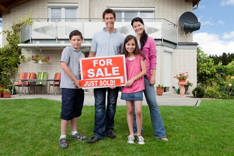 family with for sale sign outside of house