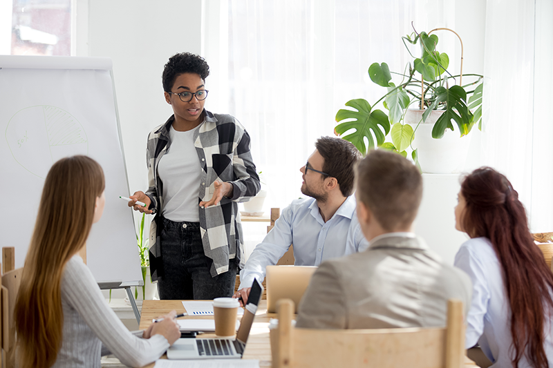 a group sitting down looking at a woman presenting