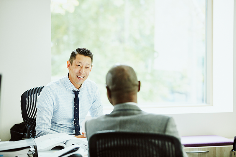 two men sitting down in an office having conversation