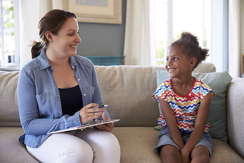 woman sitting down on a couch next to a small child