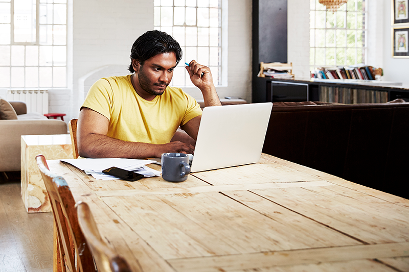 man sitting at table looking at computer