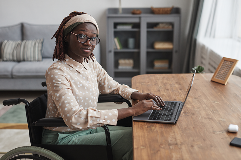 woman sitting at table on laptop looking at camera