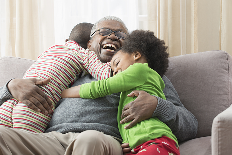 man laughing being hugged by two small children